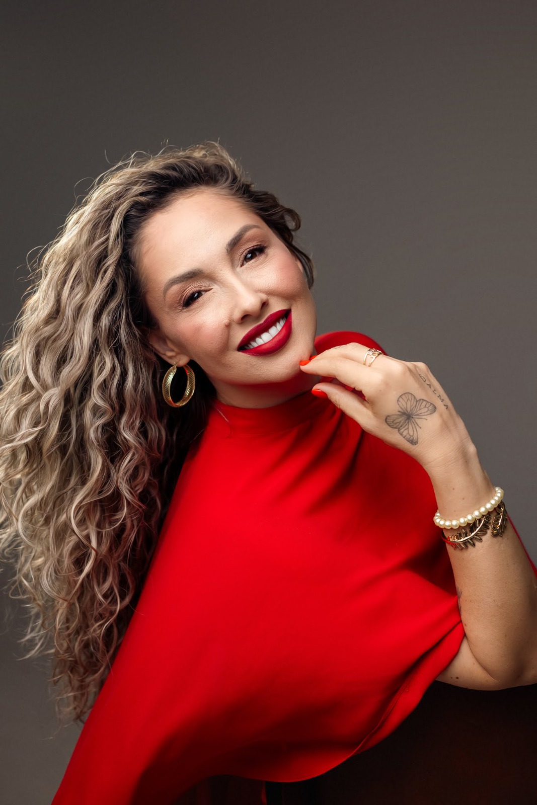 Camila Lions sorrindo, em retrato com vestido vermelho